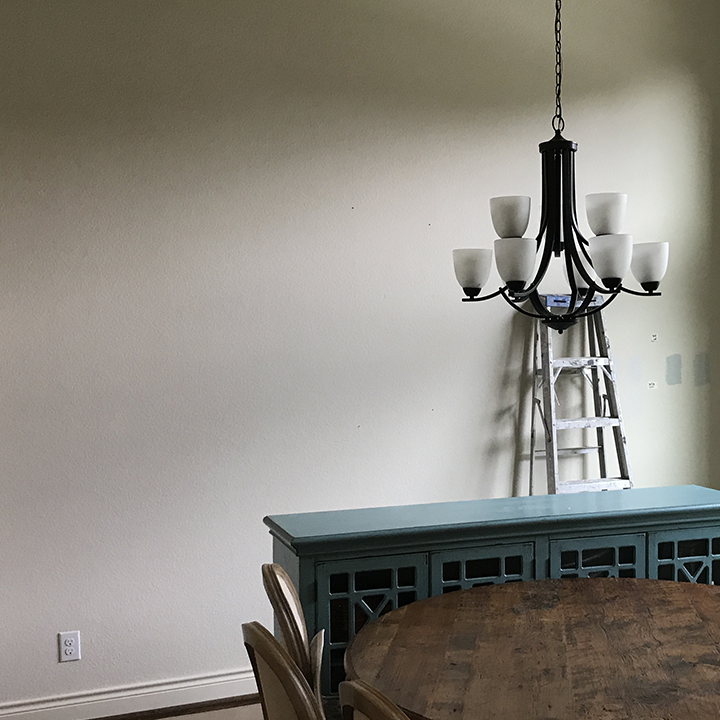 Spacious dining room with plain wall and rustic furniture.