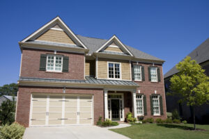 Two-story house with brick facade, tan siding, beige garage door, white trim