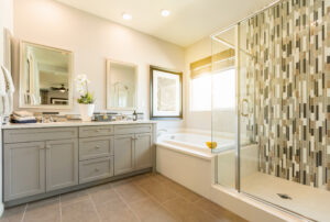 Luxury bathroom with under the sink cabinets and drawers flawlessly painted in light gray to go with beige walls and countertop and woodgrain flooring