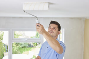 Local Interior Painters Florida man painting ceiling In room of House With Paint Roller