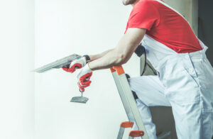 Painting Company San Antonio TX Caucasian Worker in His 30s with Patching Tools in His Hand. Drywall Patch and Preparing Interior Apartment Walls For Painting.
